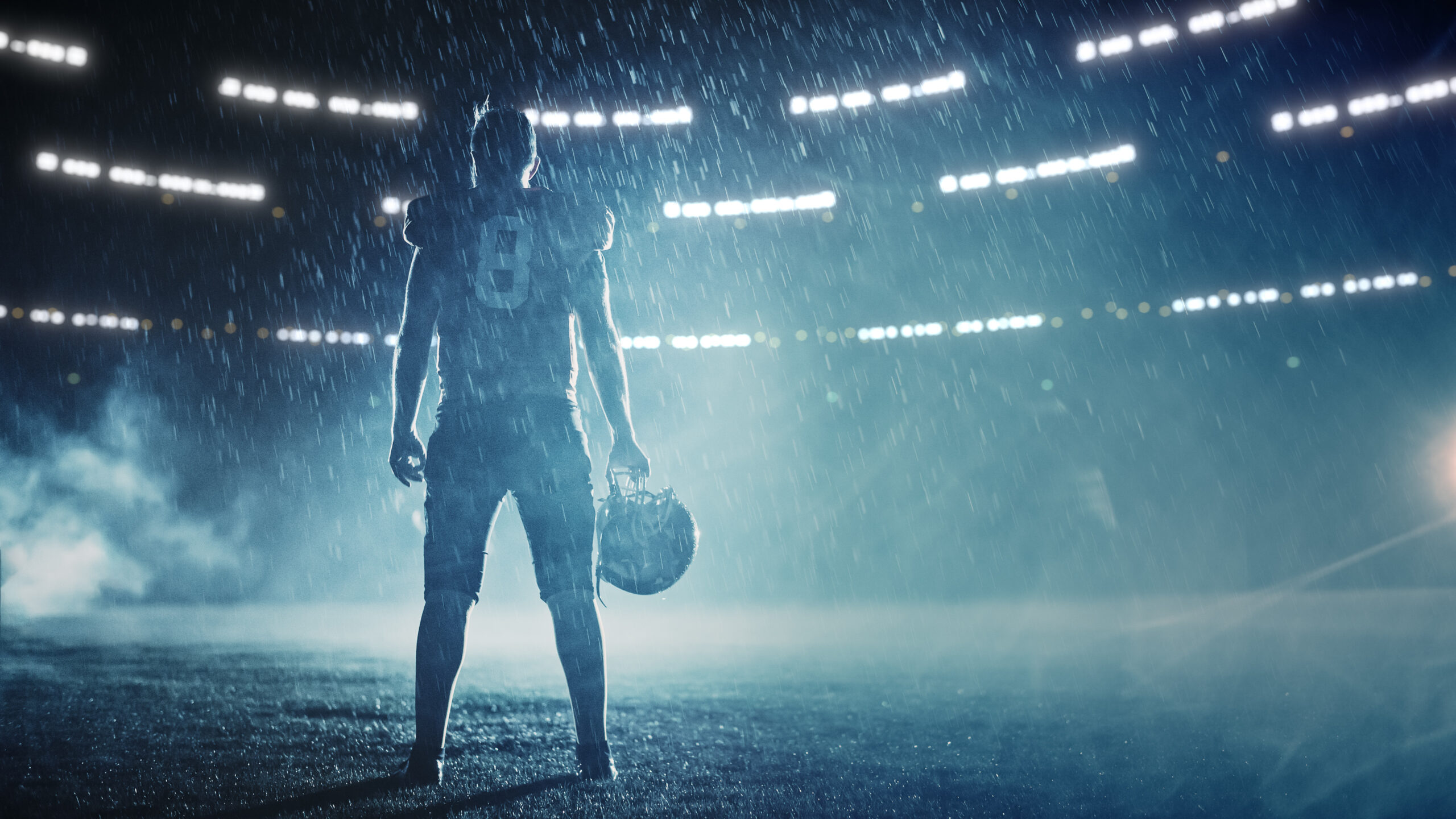 American Football Stadium: Lonely Athlete Warrior Standing on a Field Holds his Helmet.